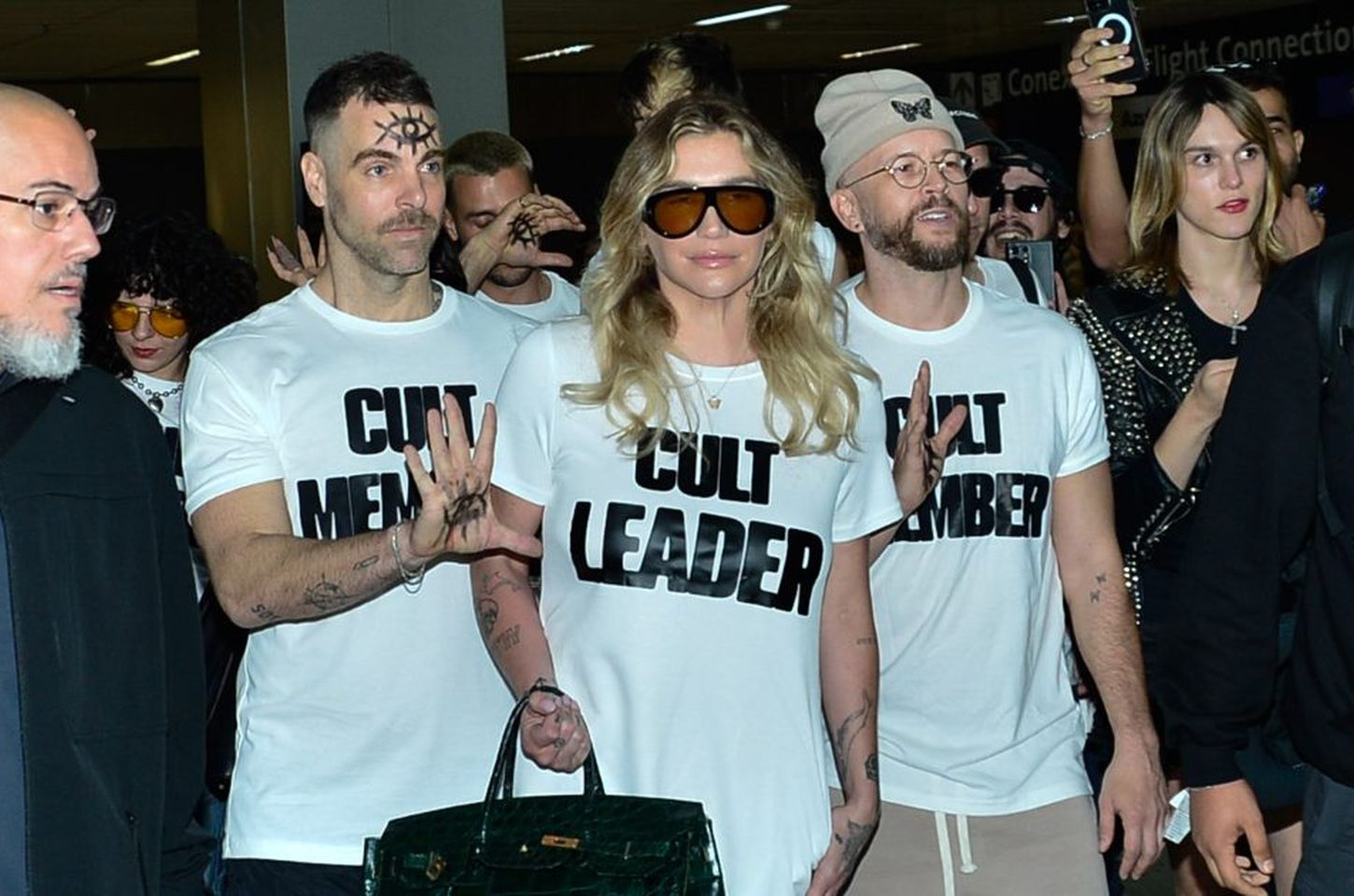 Kesha chega ao Brasil com look de 'líder do culto' e olhos nas mãos